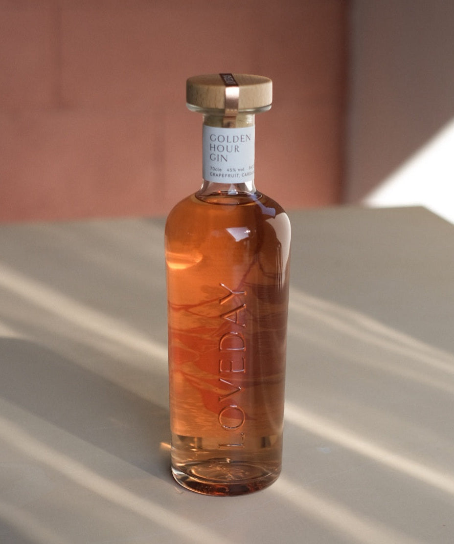 Bottle of Golden Hour Gin on a reflective surface with a blurred background