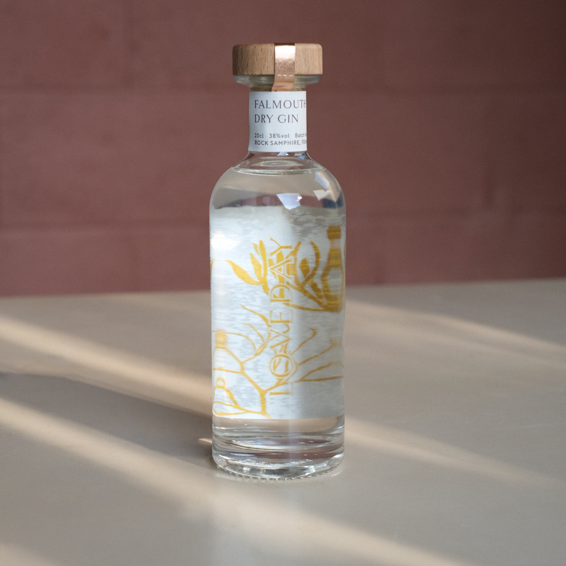 Falmouth Dry Gin 20cl bottle by Loveday Distillery with golden botanical label and wooden cap, lit by warm sunlight