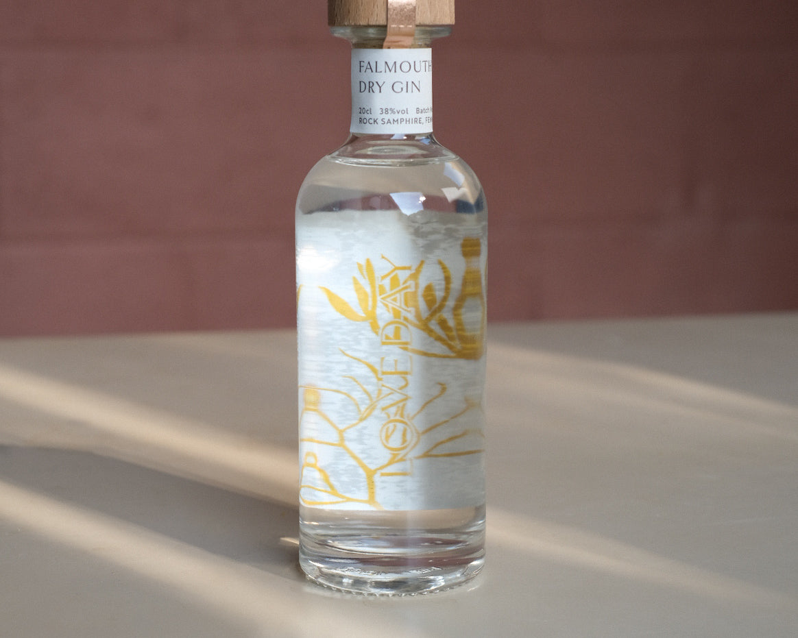 Falmouth Dry Gin 20cl bottle by Loveday Distillery with golden botanical label and wooden cap, lit by warm sunlight