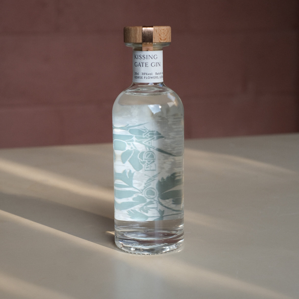 Kissing Gate Gin 30cl bottle with wooden cap and sage botanical label design, warm studio lighting