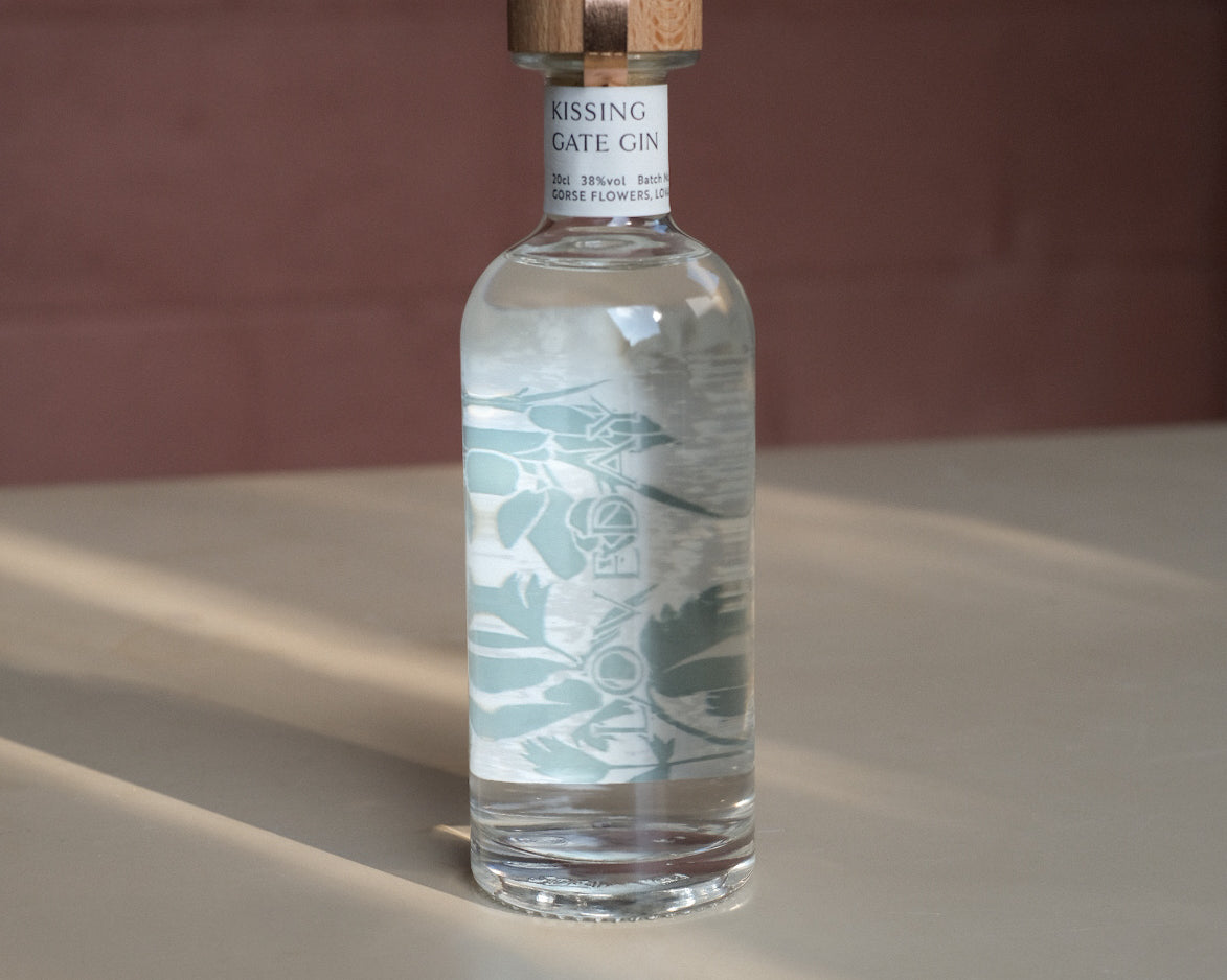 Kissing Gate Gin 30cl bottle with wooden cap and sage botanical label design, warm studio lighting