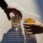 Two hands reaching for gin and tonic glasses with orange slices and dill, celebrating Falmouth Cornwall