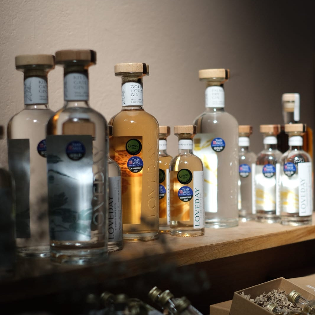 Loveday Distillery gin bottles including Golden Hour Gin displayed on a wooden shelf, with Taste of the West Champion awards
