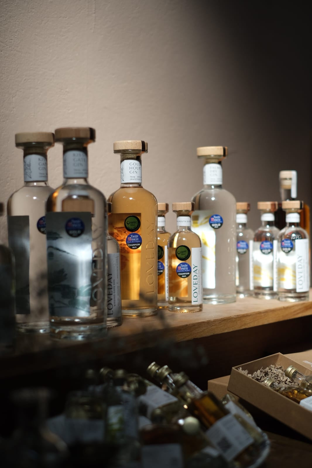 Loveday Distillery gin bottles including Golden Hour Gin displayed on a wooden shelf, with Taste of the West Champion awards