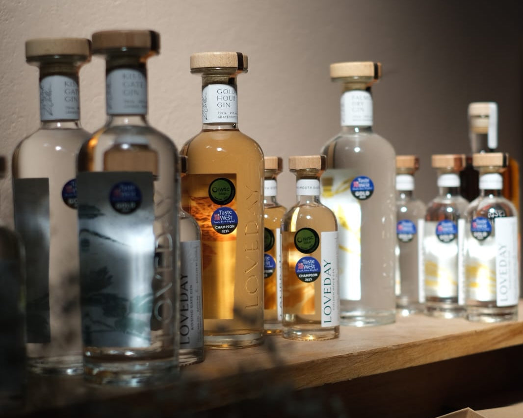 Loveday Distillery gin bottles including Golden Hour Gin displayed on a wooden shelf, with Taste of the West Champion awards