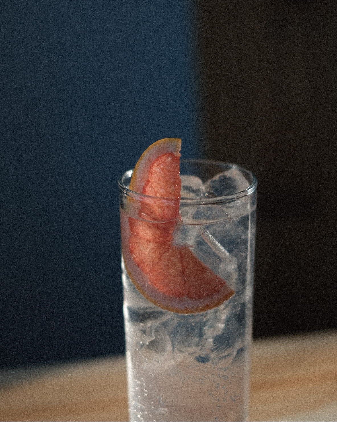 Tall glass of gin and tonic over ice with a pink grapefruit wedge garnish, served at Loveday Distillery