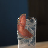 Tall glass of gin and tonic over ice with a pink grapefruit wedge garnish, served at Loveday Distillery