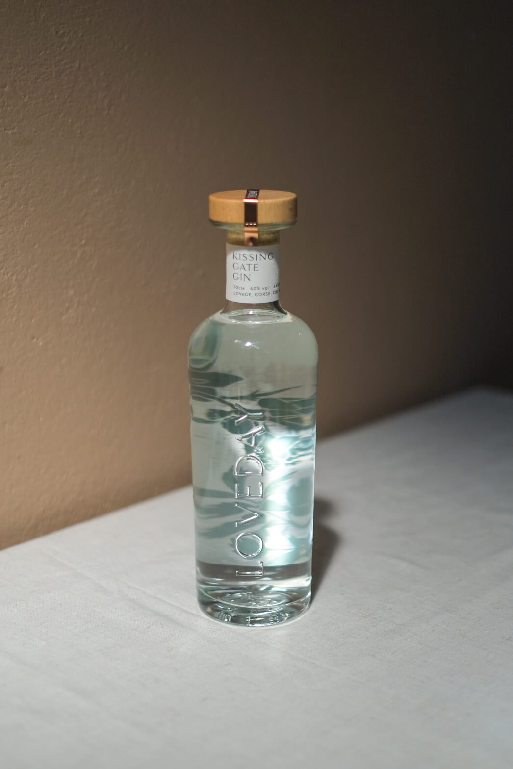 Loveday Distillery Kissing Gate Gin in a clear glass bottle with gold cap on a white surface