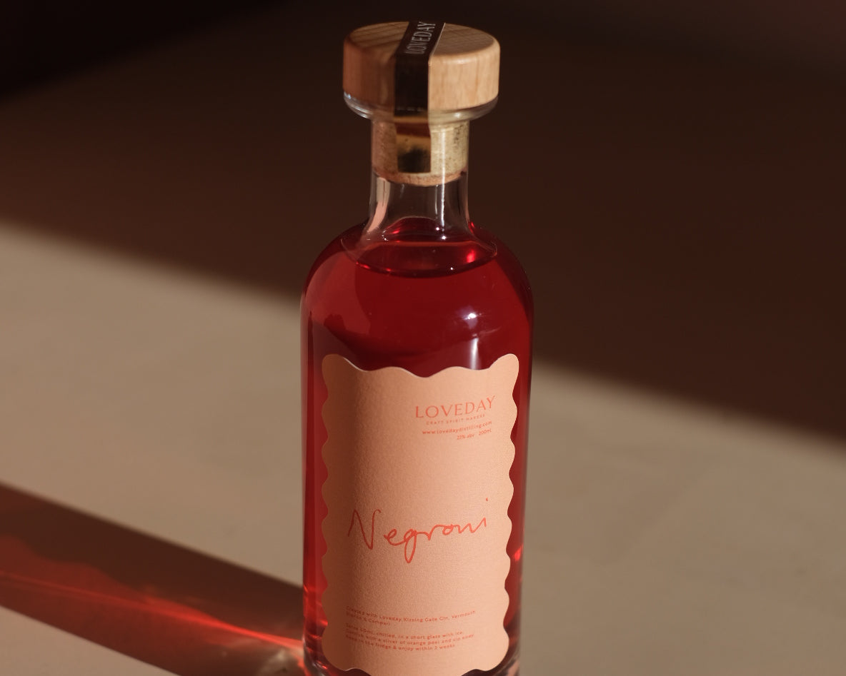 Loveday Distillery Negroni ready-to-pour bottle with ruby red liquid, scalloped peach label, and wooden cork stopper